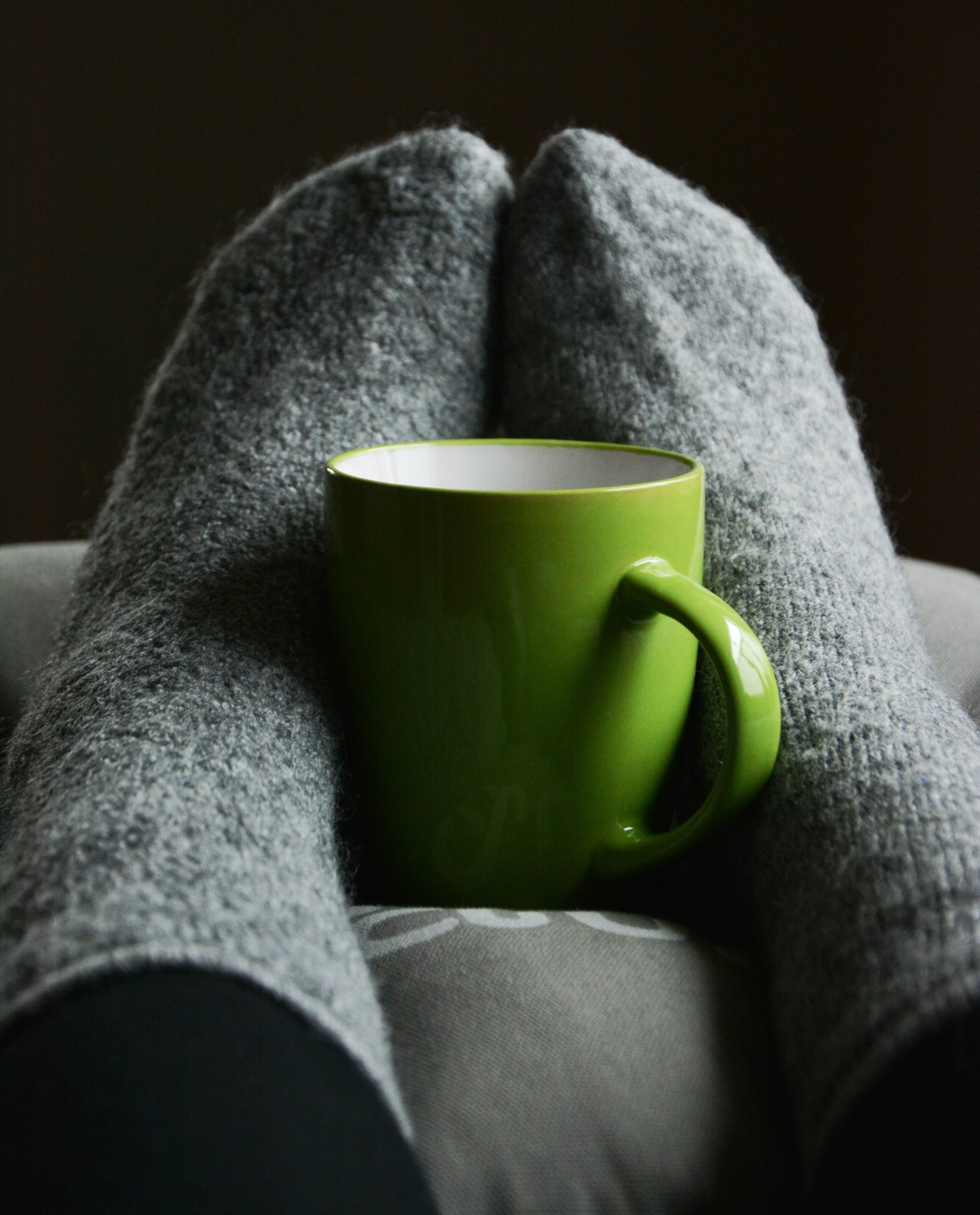 Feet in cosy socks and mug of warm drink